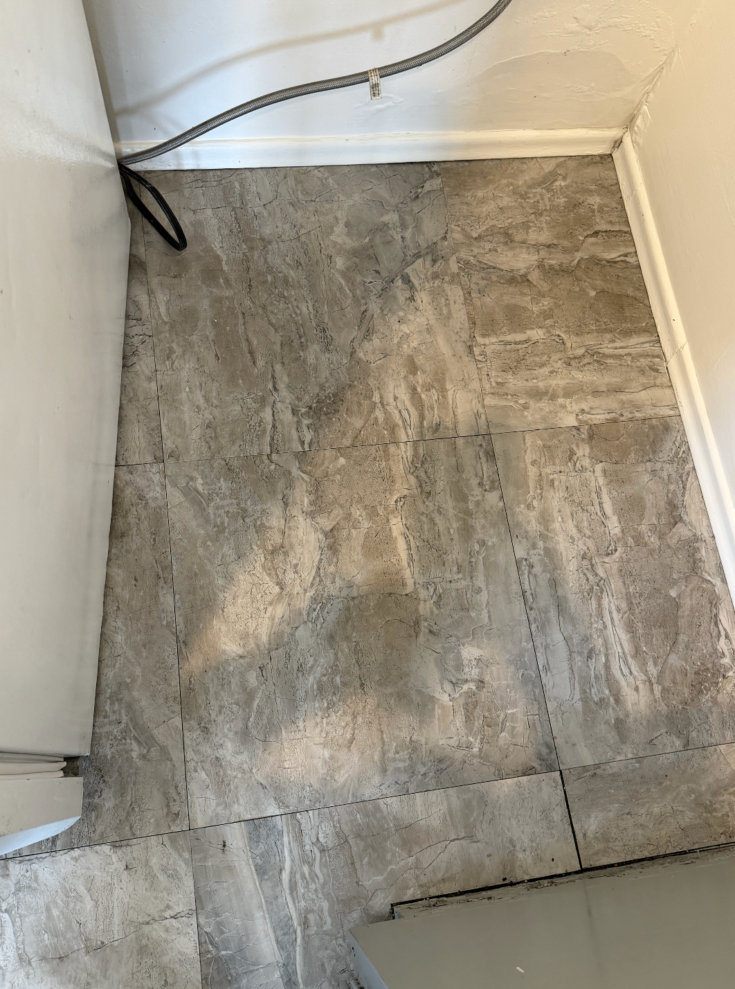 Floor behind an appliance after cleaning with the dirt and buildup removed.