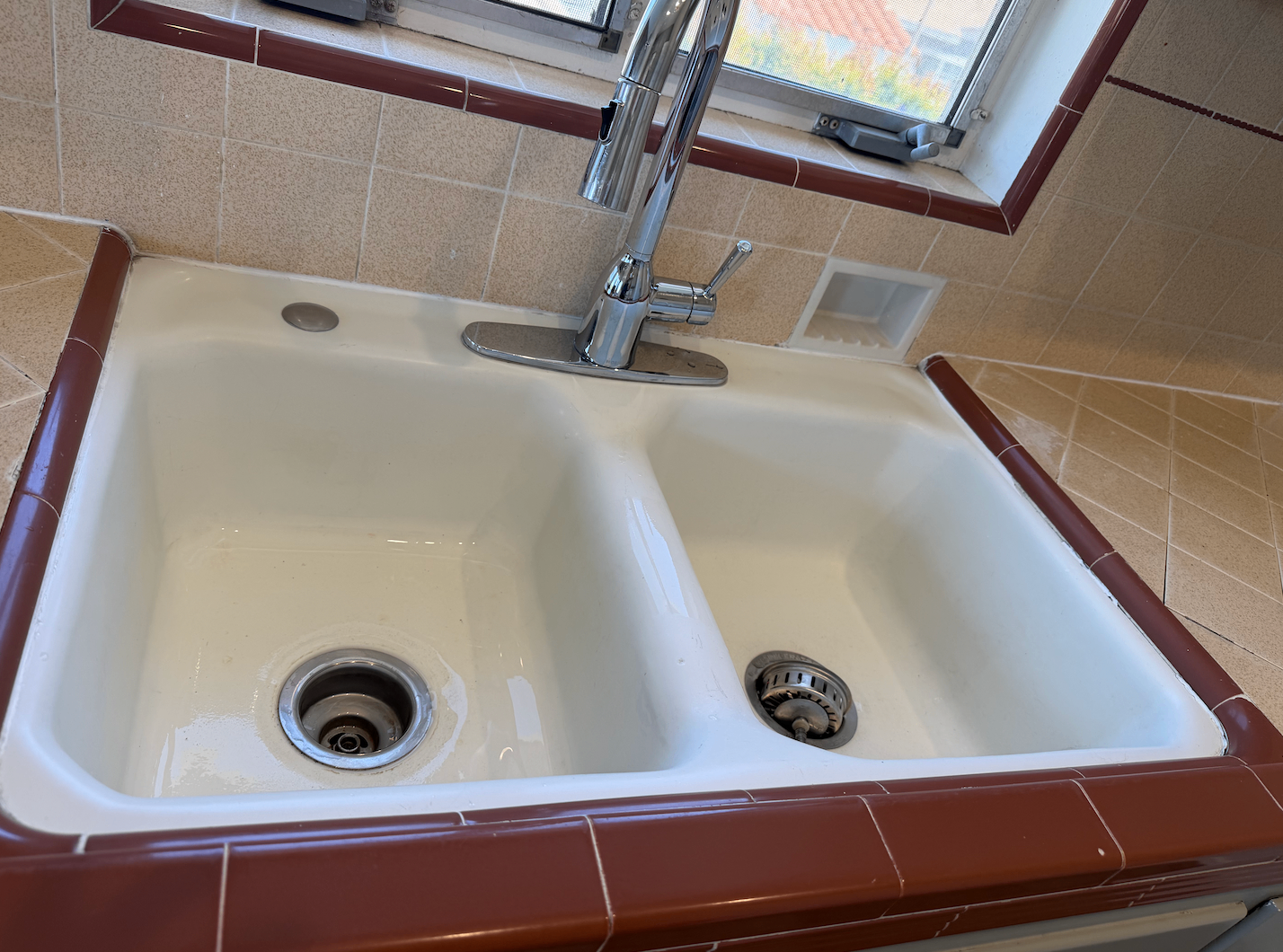 Double kitchen sink after cleaning with a bright, polished surface.